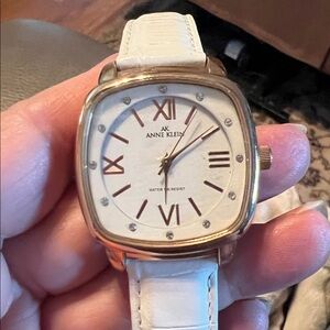 Anne Klein quartz watch with a gold-tone case, white dial with rhinestone accent